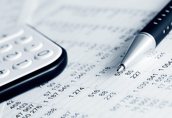 Close-up of a calculator, pen, and financial document with numbers, representing accounting or financial analysis.