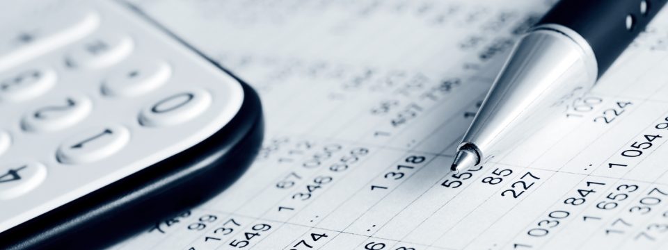 Close-up of a calculator, pen, and financial document with numbers, representing accounting or financial analysis.